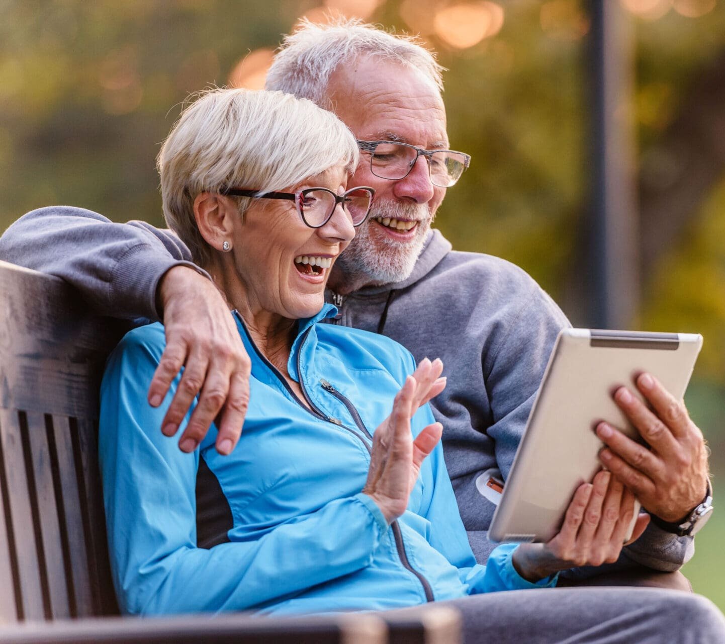 Aktivt senior par sitter på benken og ser på nettbrett